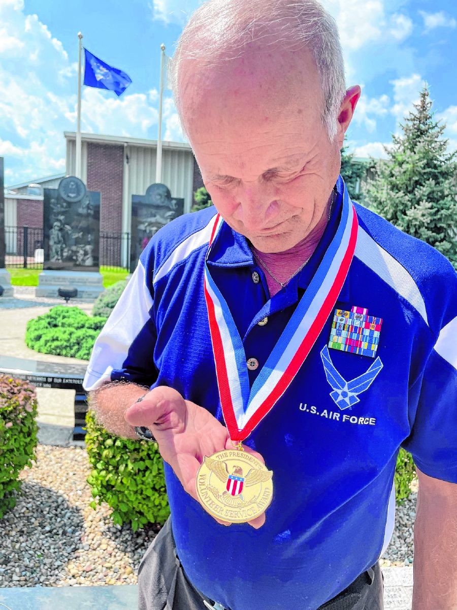 Paul Norton examines his gold medallion. He says most of his volunteer work has been through the Mayor's Advisory Council for Veterans in Indianapolis and the Indianapolis Metropolitan Military Honor Guard. (Shelley Swift | Daily Reporter)